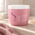 Różowy słoik Alfaparf Semi di Lino Nutritive Mask 500 ml obok jasnego grzebienia.