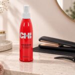 Czerwony spray CHI 44 Iron Guard 237 ml obok prostownicy i klipsa do włosów