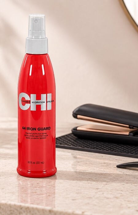 Czerwony spray CHI 44 Iron Guard 237 ml obok prostownicy i klipsa do włosów