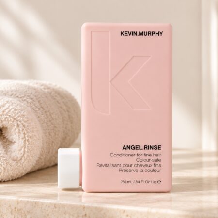 Różowa butelka odżywki Kevin Murphy Angel.Rinse 250 ml obok jasnego ręcznika