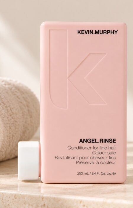 Różowa butelka odżywki Kevin Murphy Angel.Rinse 250 ml obok jasnego ręcznika