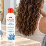 Butelka Cantu Weightless Smooth + Curl Cream 295 ml na tle falowanych włosów