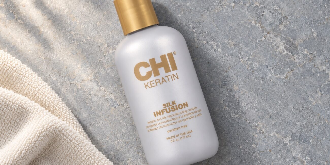 Butelka CHI Keratin Silk Infusion 177 ml ze złotą nakrętką obok ręcznika