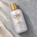 Butelka CHI Keratin Silk Infusion 177 ml ze złotą nakrętką obok ręcznika