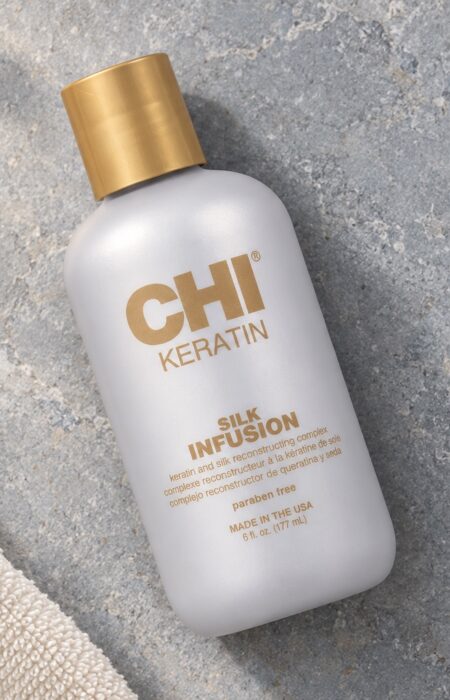 Butelka CHI Keratin Silk Infusion 177 ml ze złotą nakrętką obok ręcznika