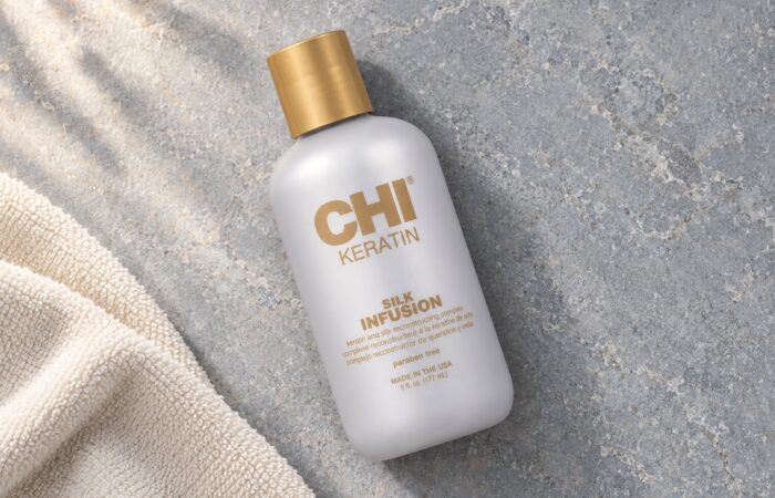 Butelka CHI Keratin Silk Infusion 177 ml ze złotą nakrętką obok ręcznika