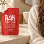 Czerwone opakowanie Eleven Australia Miracle Hair Mask 200 ml przy ręczniku i wilgotnych włosach