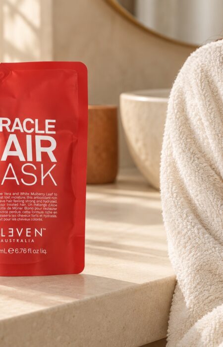 Czerwone opakowanie Eleven Australia Miracle Hair Mask 200 ml przy ręczniku i wilgotnych włosach
