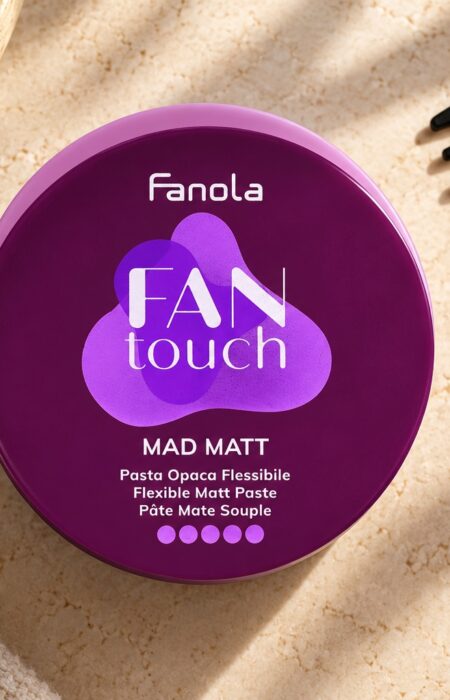 Fioletowe opakowanie pasty Fanola Mad Matt obok czarnego grzebienia.