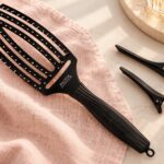 Czarna szczotka Olivia Garden Finger Brush Combo Medium i dwa klipsy do wydzielania pasm.