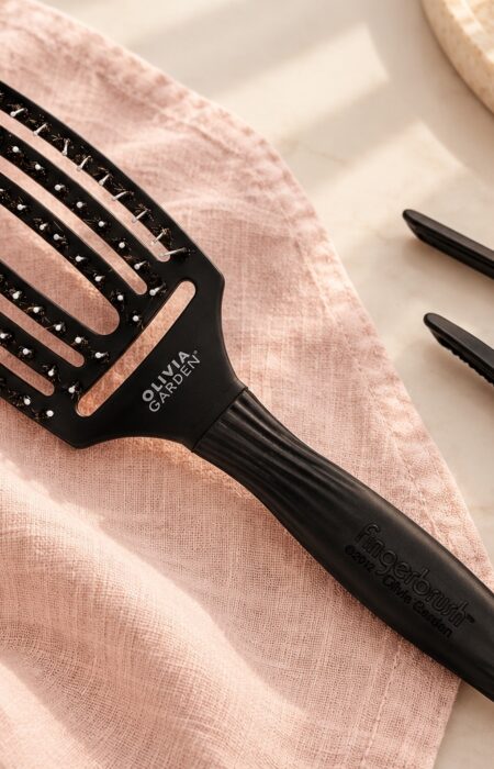 Czarna szczotka Olivia Garden Finger Brush Combo Medium i dwa klipsy do wydzielania pasm.