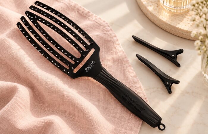 Czarna szczotka Olivia Garden Finger Brush Combo Medium i dwa klipsy do wydzielania pasm.