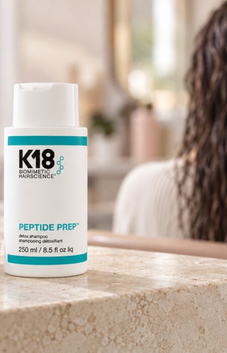 Butelka K18 Peptide Prep Detox Shampoo 250 ml obok ręcznika, z wilgotnymi włosami w tle
