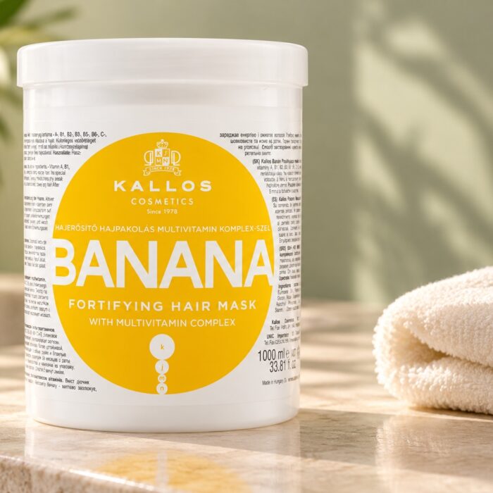 Biały słoik maski Kallos Banana z żółtą etykietą obok jasnego ręcznika