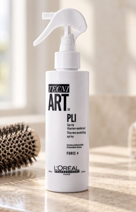 Biała butelka L’Oréal Tecni.ART Pli obok szczotki i wałków do modelowania włosów