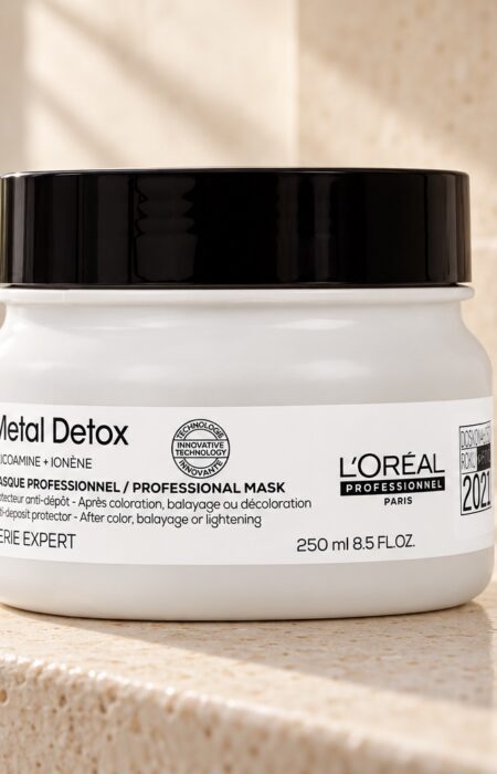 Słoik maski L’Oréal Metal Detox 250 ml z czarną pokrywką obok złożonego ręcznika.