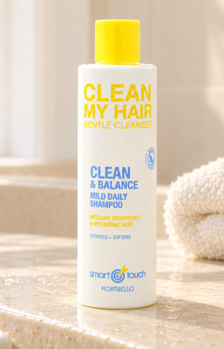 Biała butelka Montibello Clean My Hair z żółtą nakrętką na jasnym blacie obok ręcznika.