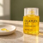 Butelka Olaplex No.7 Bonding Oil 30 ml i dwie krople olejku na ceramicznym naczyniu