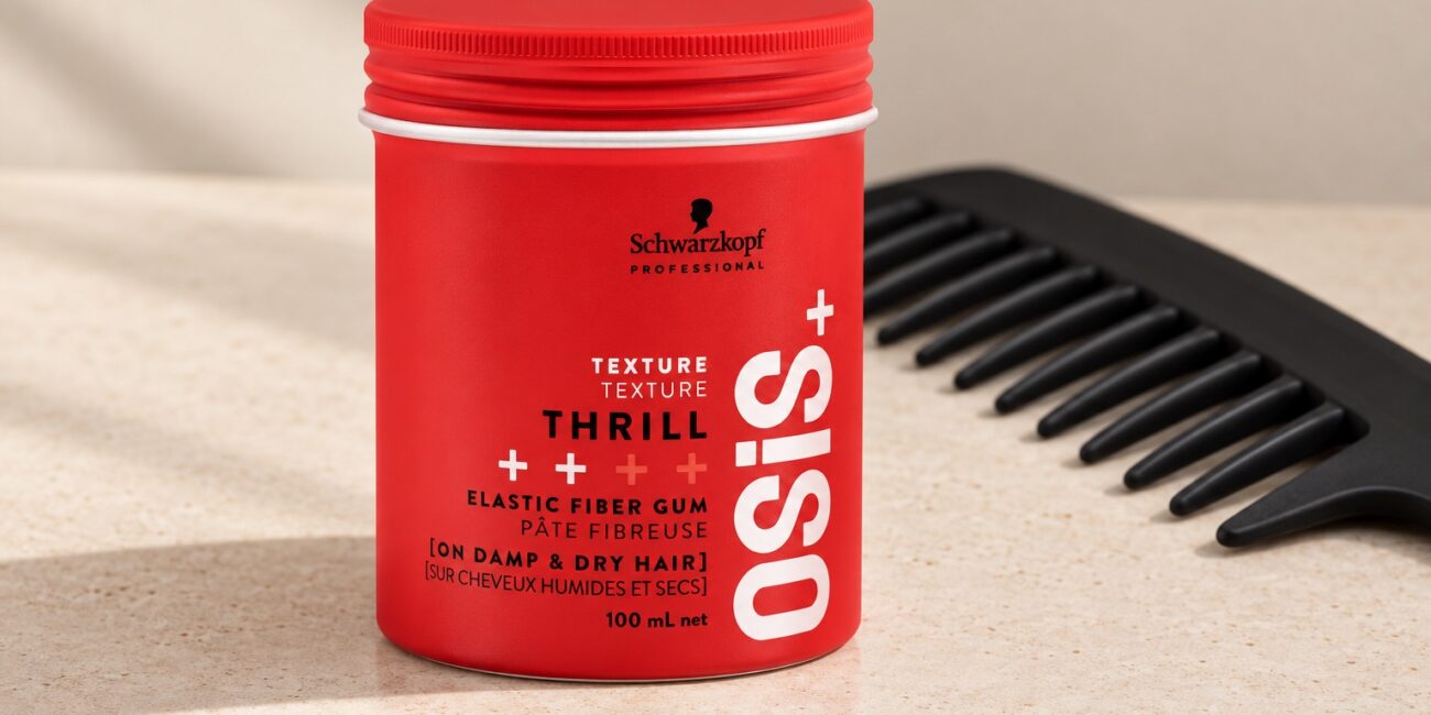 Czerwony słoiczek Schwarzkopf OSiS Thrill 100 ml przy czarnym grzebieniu na jasnym blacie