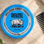 Niebieska puszka Reuzel Strong Hold Water Soluble 95 g obok grzebienia.