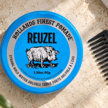 Niebieska puszka Reuzel Strong Hold Water Soluble 95 g obok grzebienia.