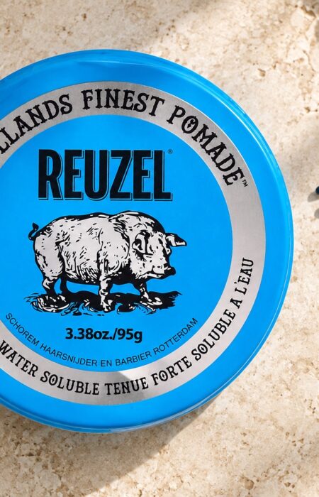 Niebieska puszka Reuzel Strong Hold Water Soluble 95 g obok grzebienia.