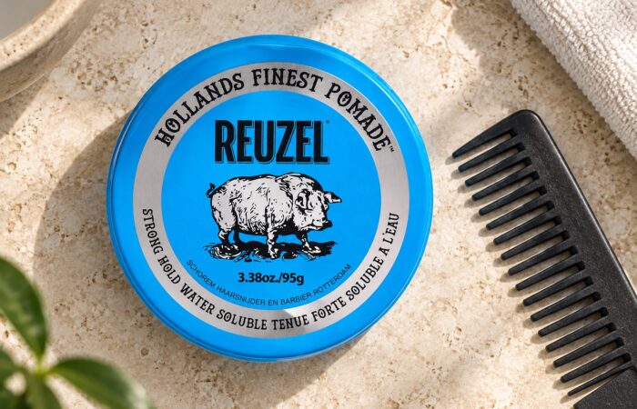 Niebieska puszka Reuzel Strong Hold Water Soluble 95 g obok grzebienia.