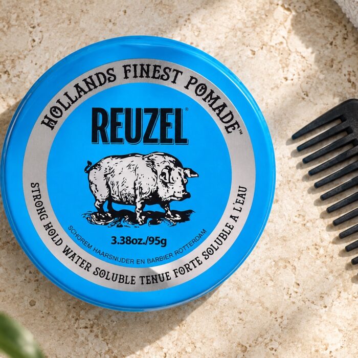 Niebieska puszka Reuzel Strong Hold Water Soluble 95 g obok grzebienia.