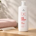 Biała butelka Schwarzkopf BC Repair Rescue Conditioner Arginine 1000 ml z grzebieniem i różowym ręcznikiem