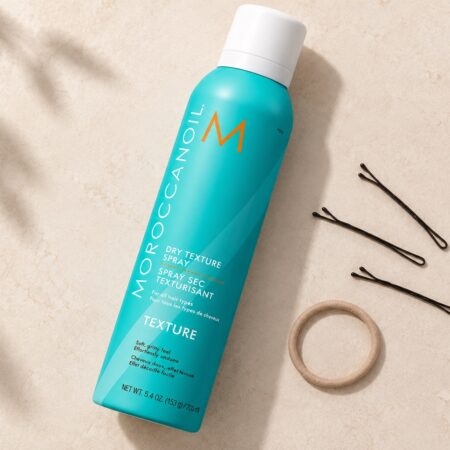 Turkusowy spray Moroccanoil Dry Texture 205 ml z białą nasadką obok wsuwek i gumki.