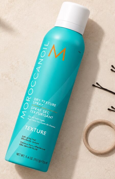 Turkusowy spray Moroccanoil Dry Texture 205 ml z białą nasadką obok wsuwek i gumki.