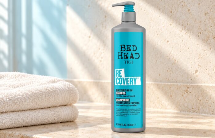Szara butelka TIGI Bed Head Recovery 970 ml z turkusową etykietą obok jasnych ręczników