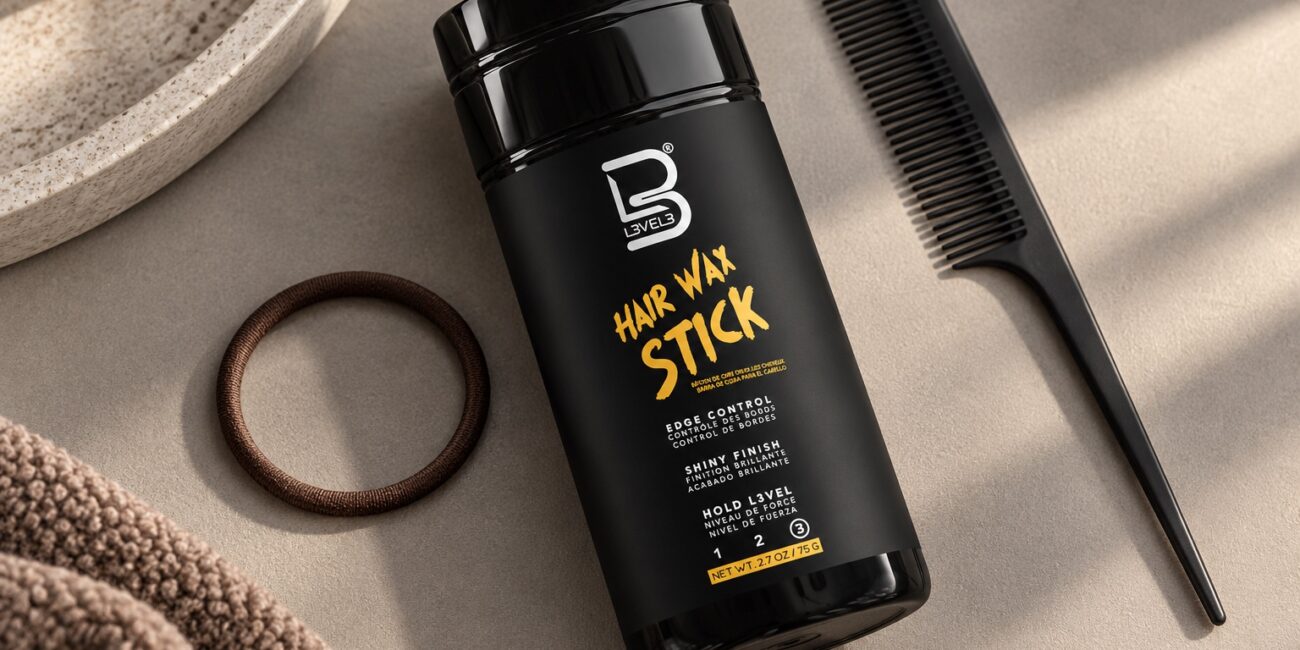 Czarny sztyft L3VEL3 Hair Wax Stick 75 g obok grzebienia i miękkiej gumki do włosów.