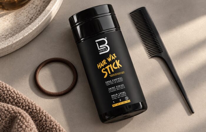 Czarny sztyft L3VEL3 Hair Wax Stick 75 g obok grzebienia i miękkiej gumki do włosów.